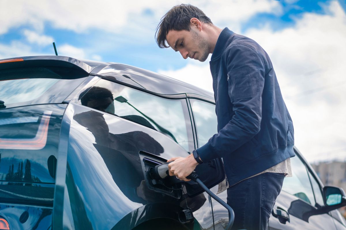a business man plugs in his electric vehicle charger
