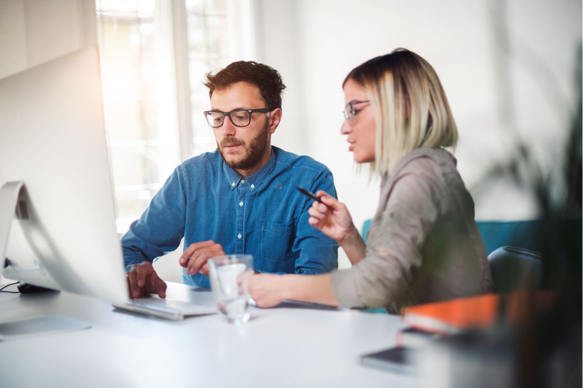 two business owners researching how long does it take to change energy supplier on a laptop in an office