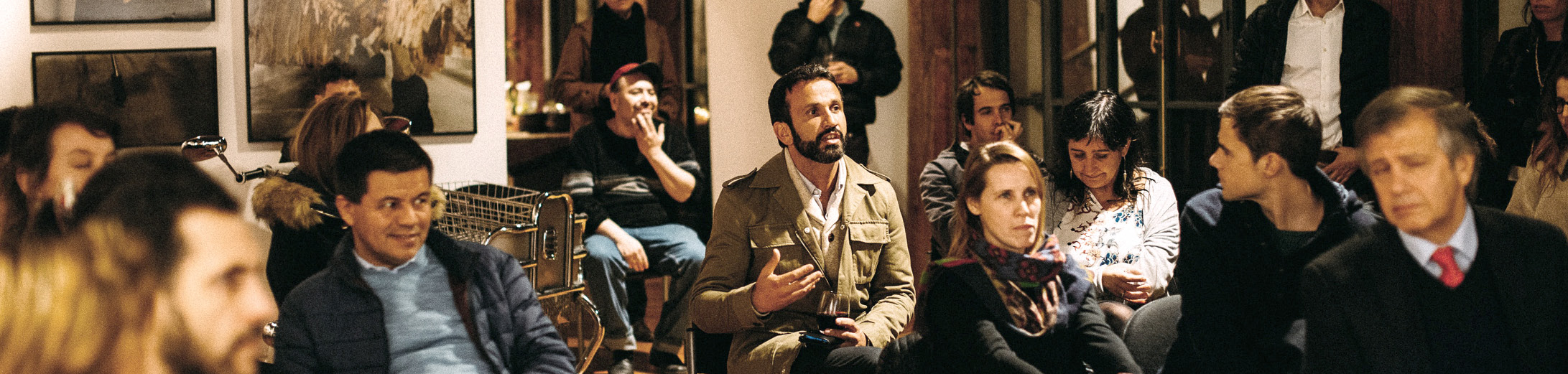 A photo showing a meeting taking place in an art gallery, with a collection of people of different ages and races. The photo goes alongside the article 'how to create new revenue streams'