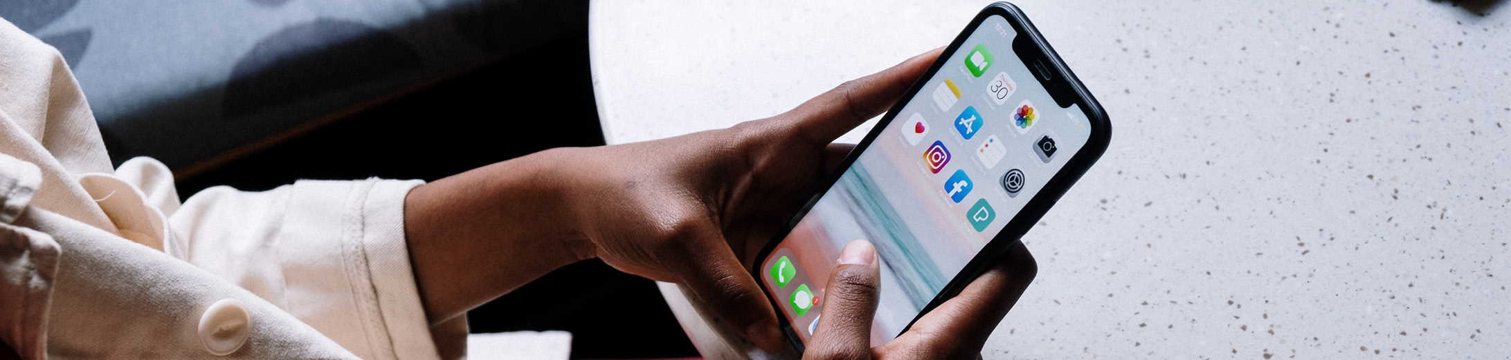 closeup of hands holding a mobile phone with multiple social media icons showing