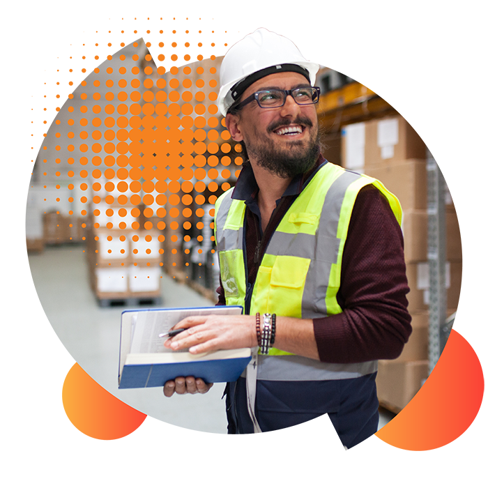 A smiling male business owner looks up at the shelves in his warehouse whilst thinking about his competitive commercial energy prices