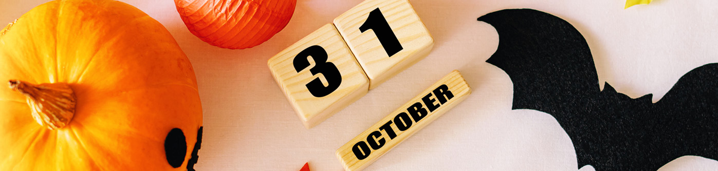 the number 31 shown in wooden blocks with a wooden block saying october surrounded by pumpkins, bats and autumn leaves, representing halloween marketing
