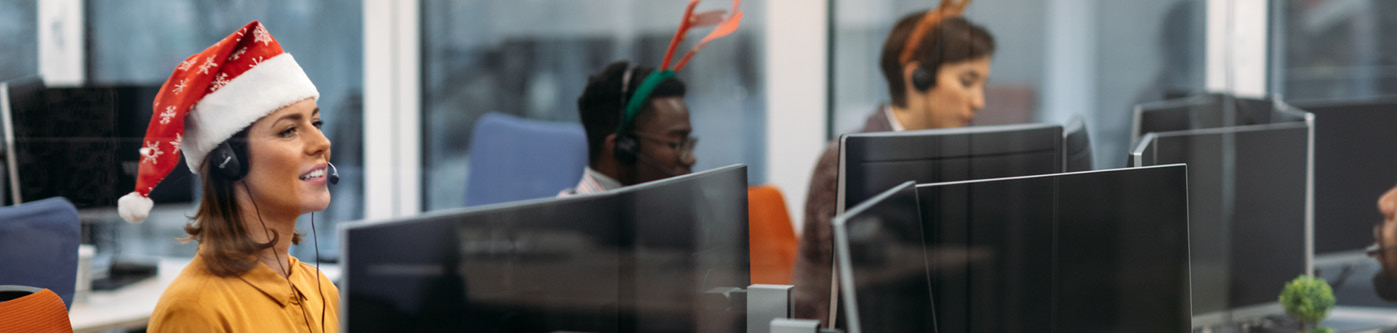 Workers in a call centre wearing christmas hats and festive headbands