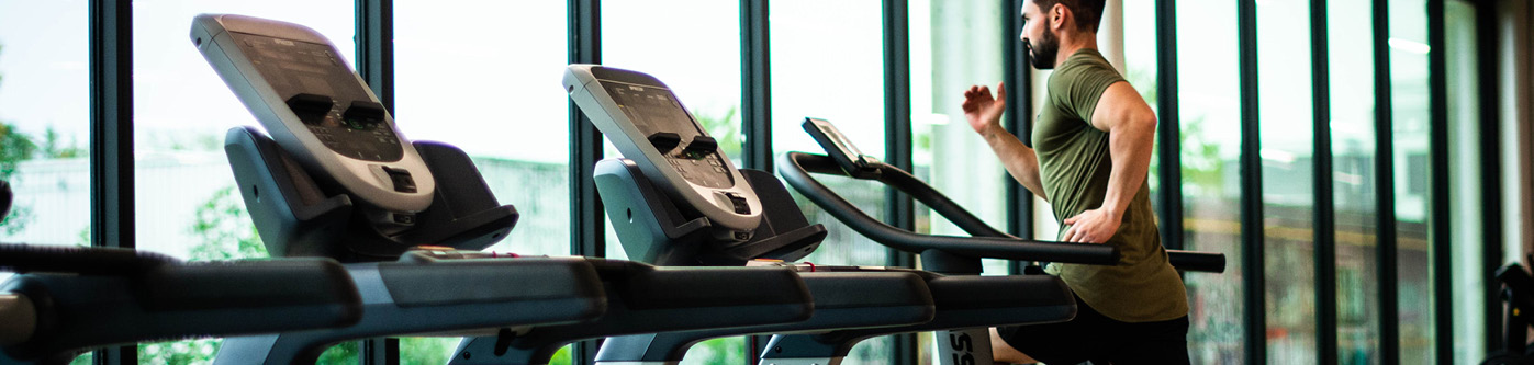Someone running on a treadmill with unused treadmills in the foreground. Reducing energy consumption for leisure centres