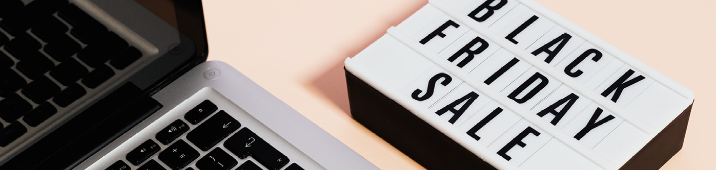 Close up of a laptop with a light box next to it spelling out 'black friday sale'