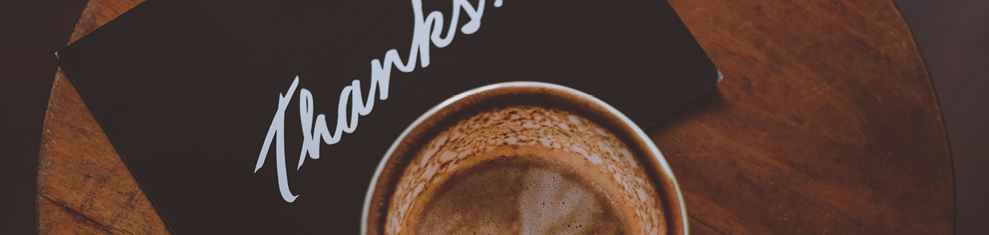 A black thank you loyalty card under a cup of coffee