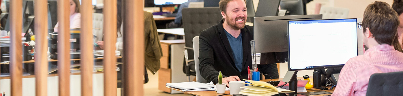 a zoomed out view of office workers at their desks, using desktop computers