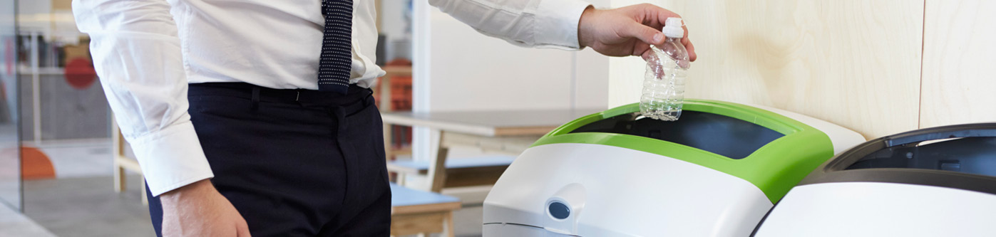 a business man is placing a plastic bottle in a plastic recycling bin