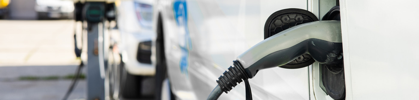 close up of white electric vans plugged into chargers