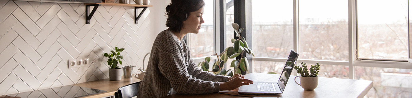 a woman sat in her kitchen on a laptop, working from home