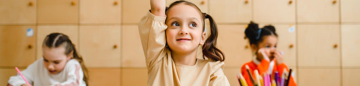 a young primary school student raising her hand in class to discuss energy saving activities