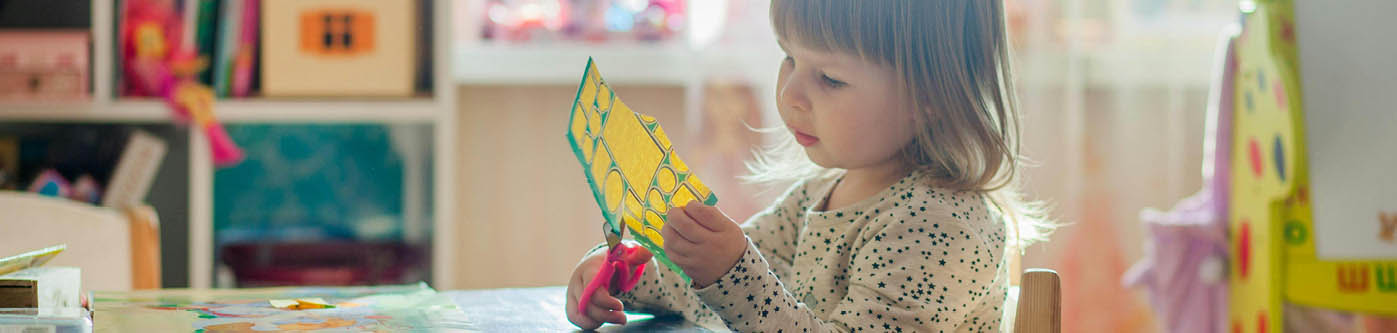 teaching younger pupils about energy efficiency - a young girl is sat at a table at school, cutting out pieces of paper
