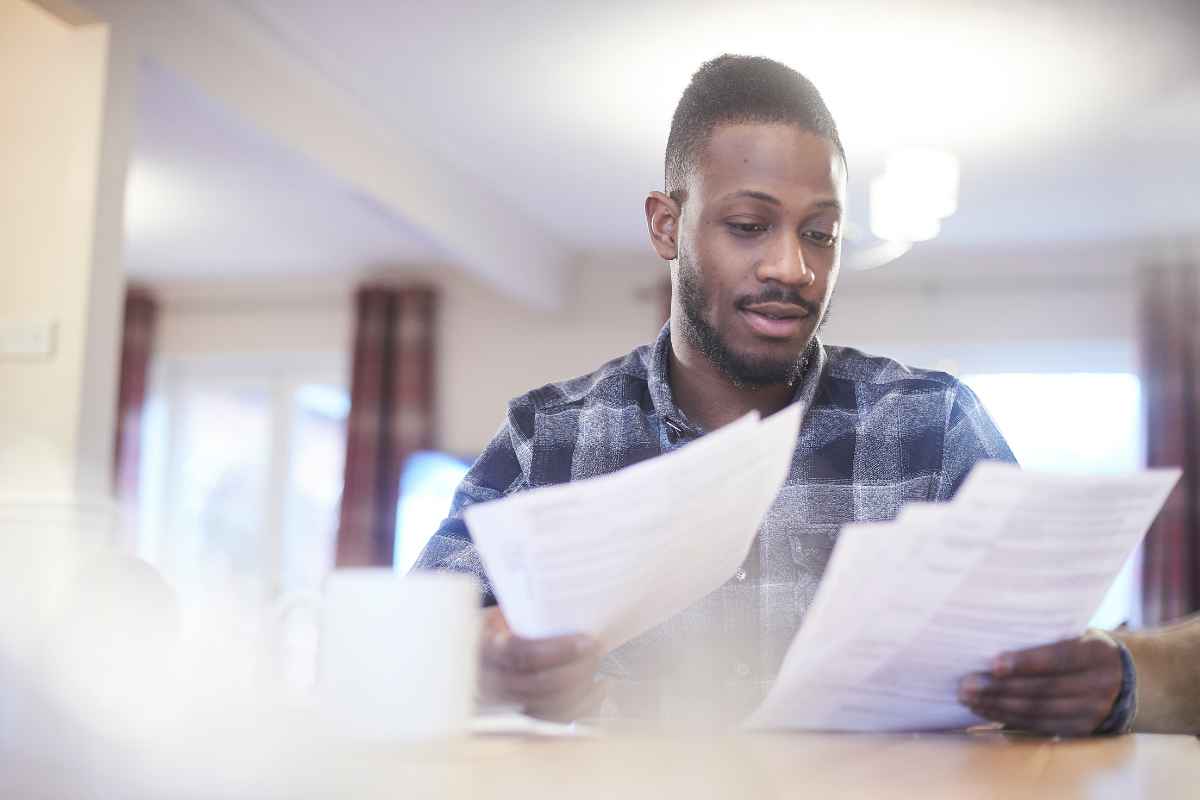 a man in a blue check shirt looking at his energy bills and adding to his business checklist