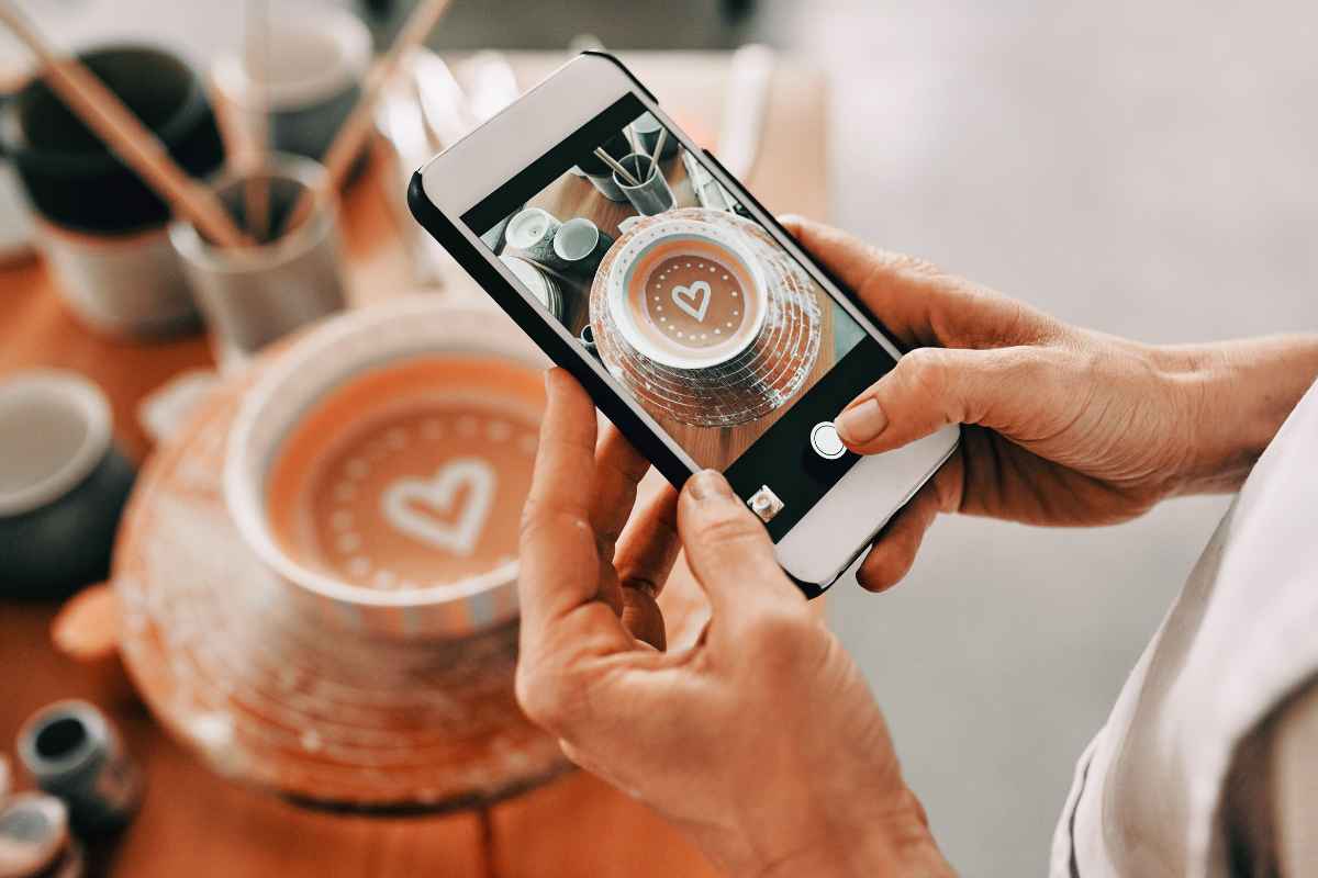 A business owner taking a photo of the bowl she has made - it is a terracotta bowl with a white heart in the centre. It illustrates the point of stepping up social media for the new year