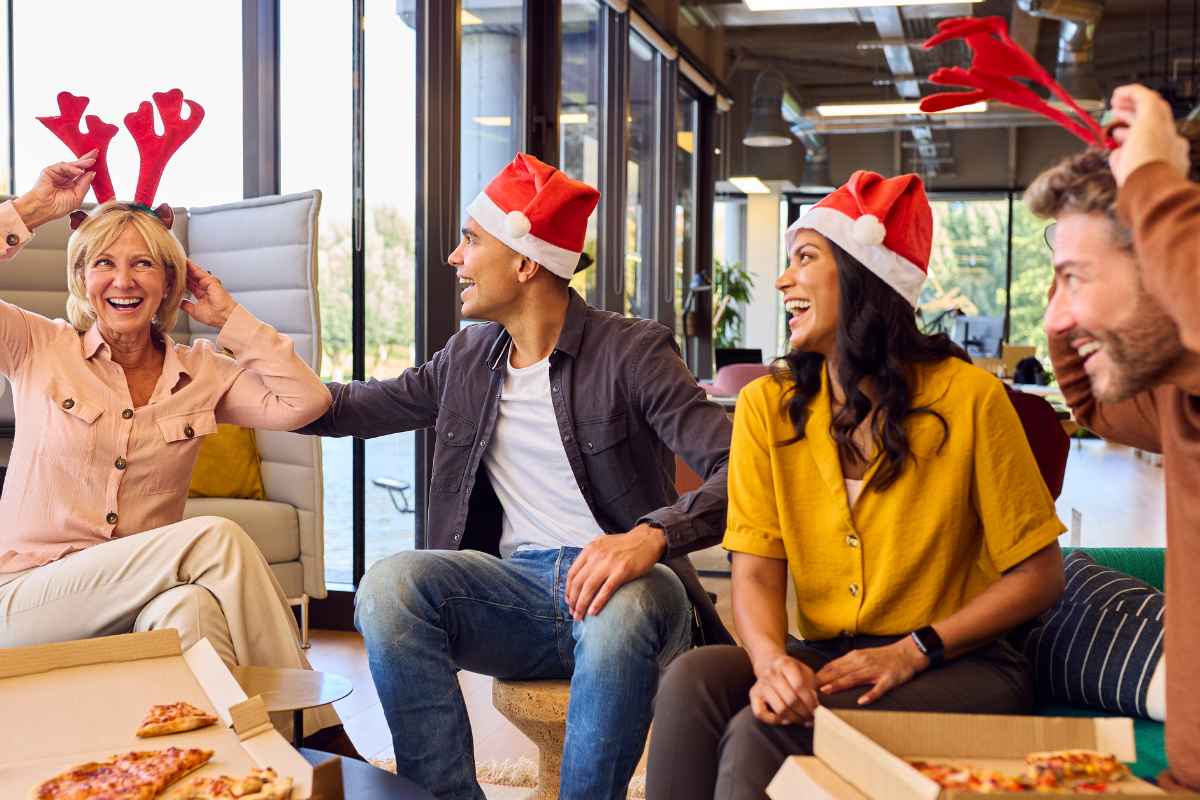 Staff celebrating the year whilst planning their next year for business - a group of colleagues laughing, dressed in christmas outfits and eating pizza