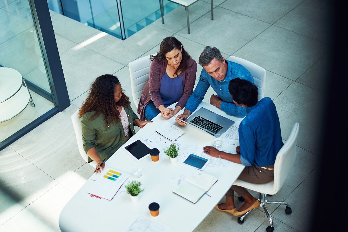 four business people sat around a table discussing their business' website requirements.