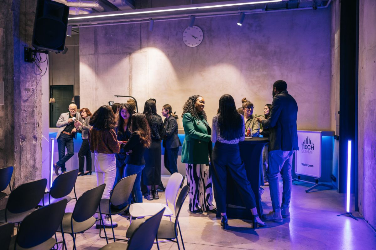 crowd of people standing at an exhibition stand