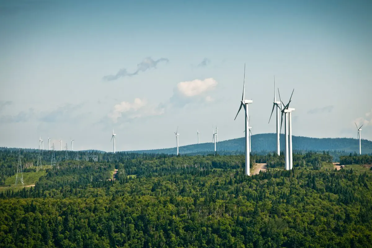 wind turbines on a hillside with blue sky behind