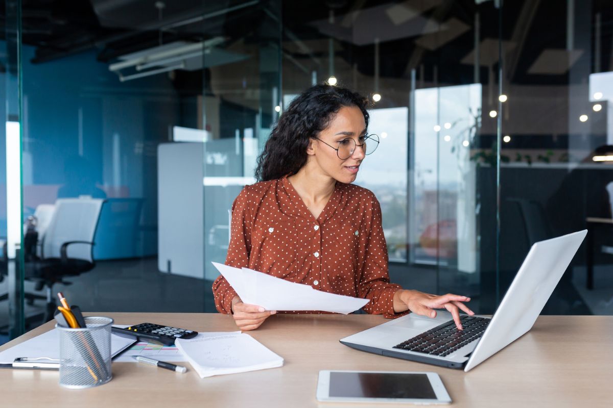 woman looking at laptop and doing paperwork